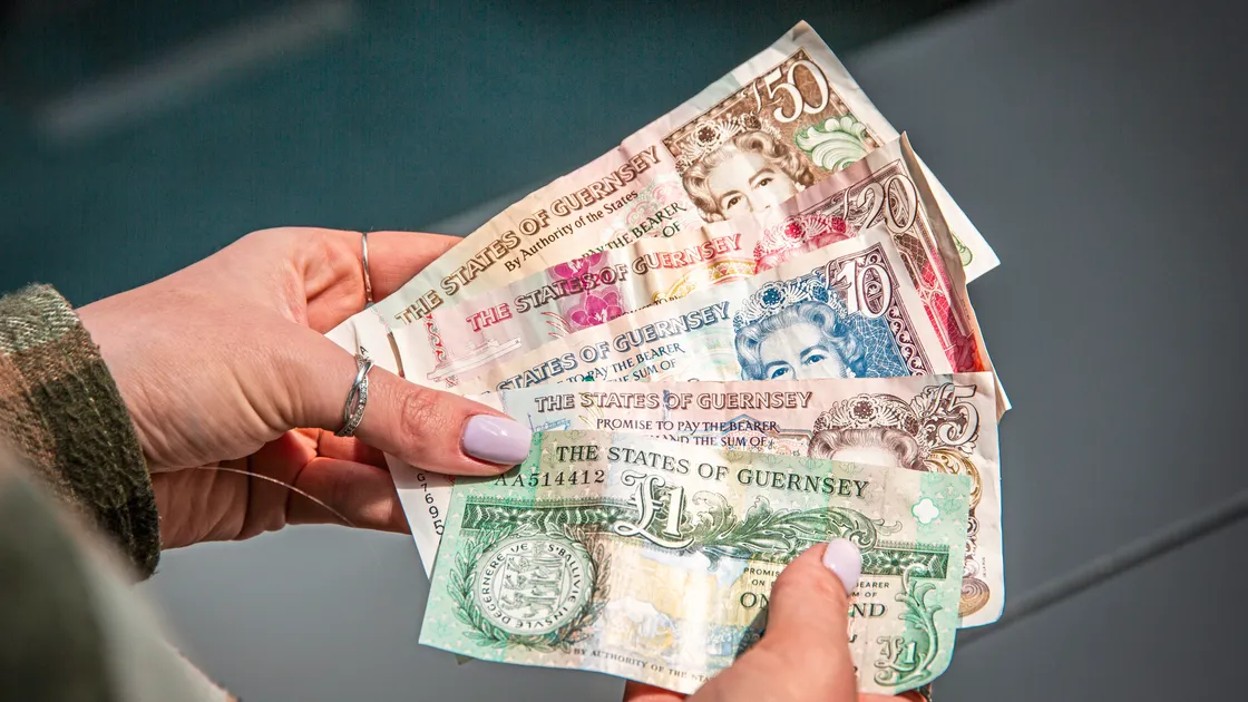 Hand holding States of Guernsey banknotes